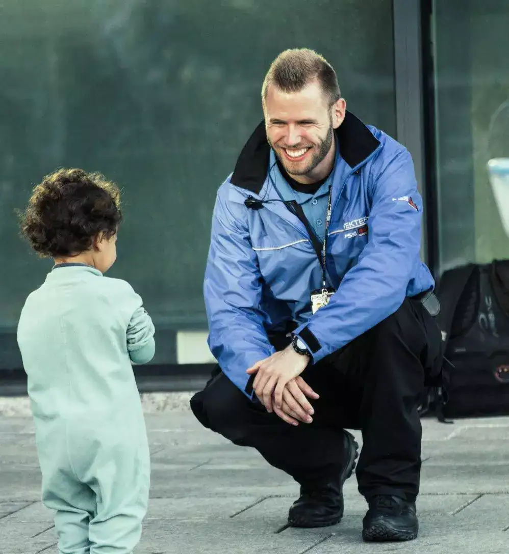 Barnehageansatt i samtale med liten gutt utenfor barnehagen.